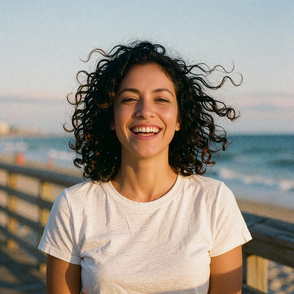 Laughing Latina woman in a white t-shirt on a seaside boardwalk, avatar for a sample travel conversation starter